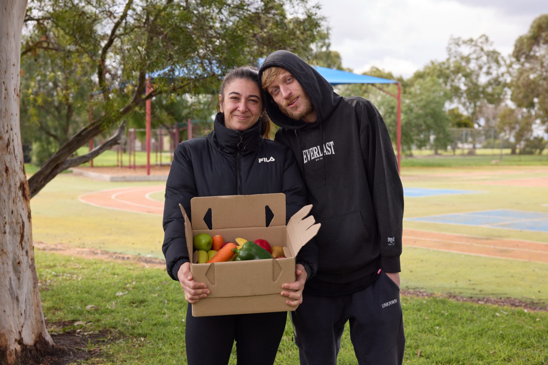Two students holding a box of fresh produce on campus