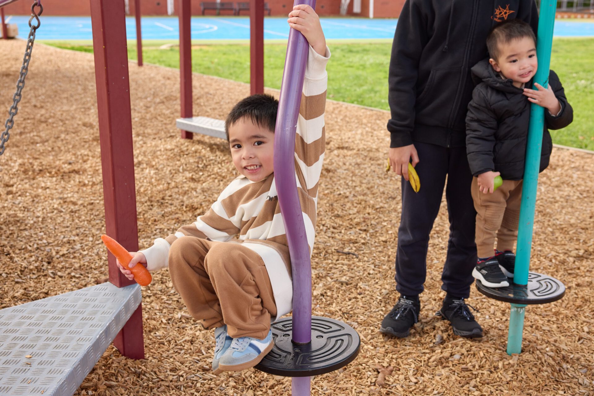 A child on a playground swing with a parent