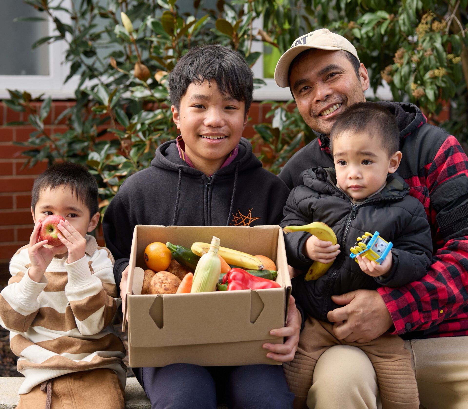 A father and his children with a box of fresh produce