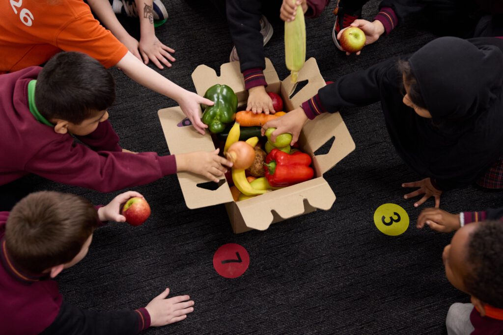 Hands packing a box of fresh produce