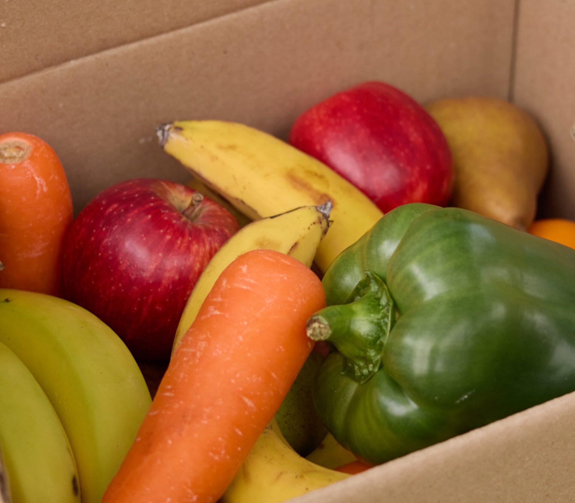 A box of fresh apples, bananas, carrots and capsicum