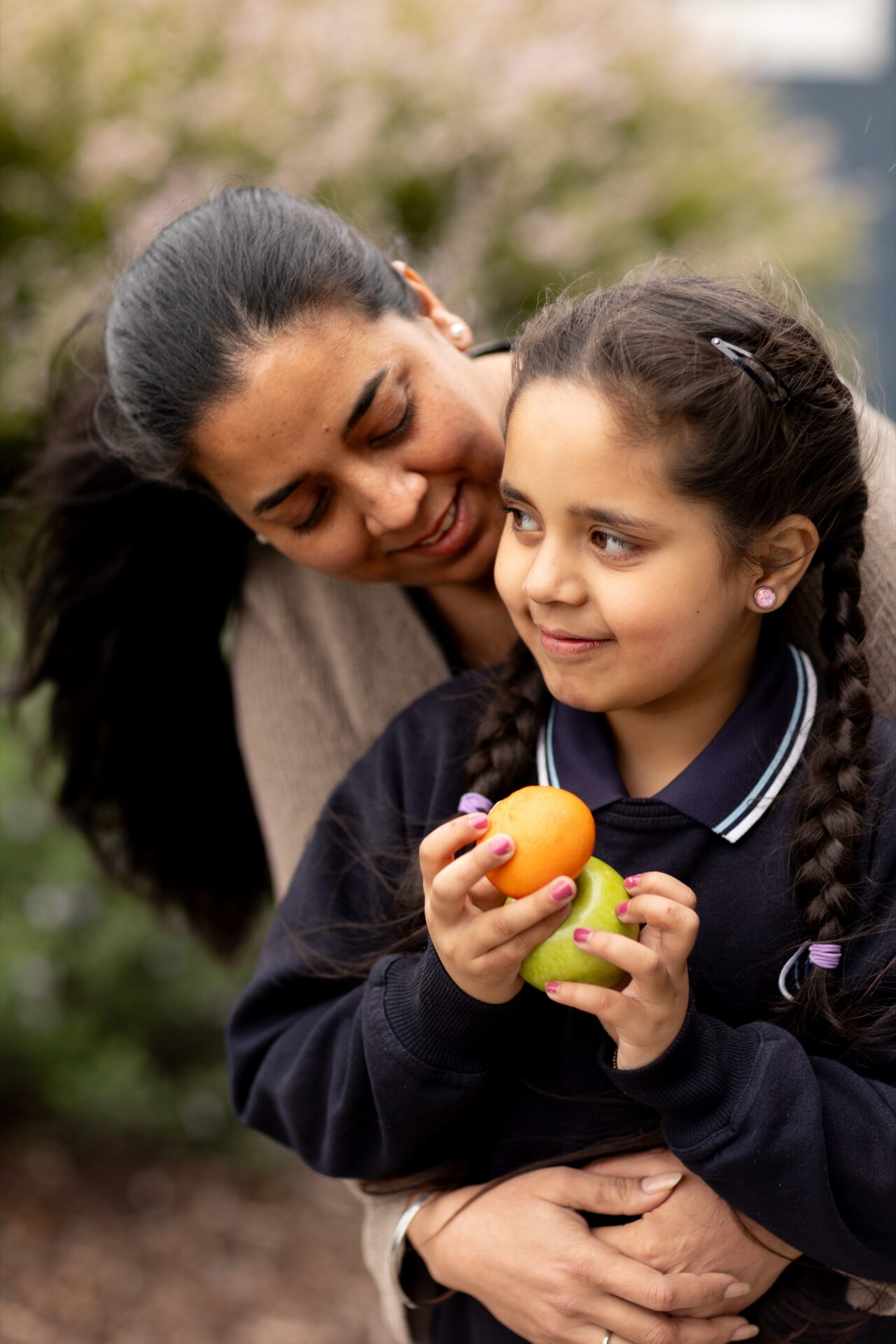 A young girl holding an orange with her mother