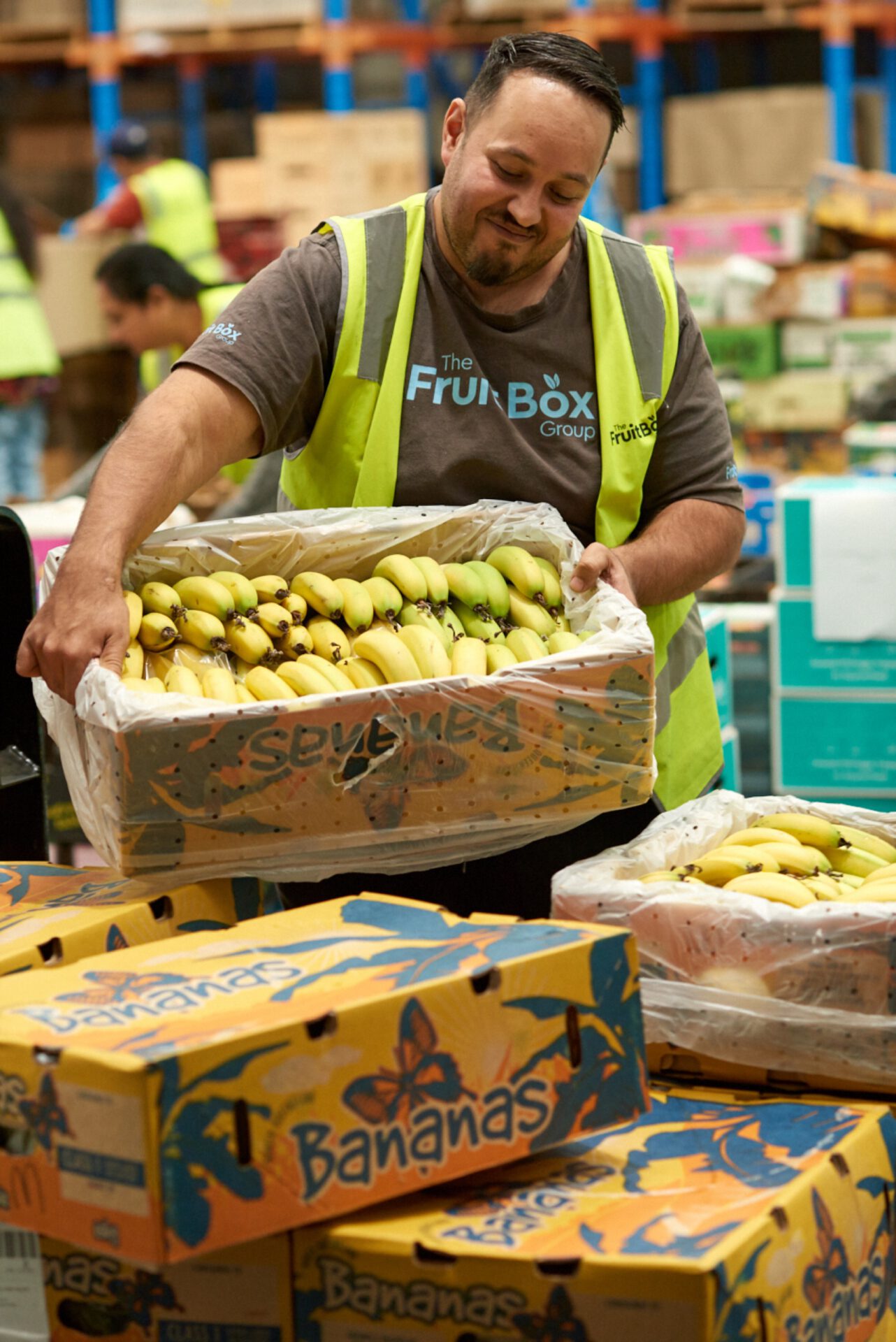A Fruit Box team member carrying a crate of bananas