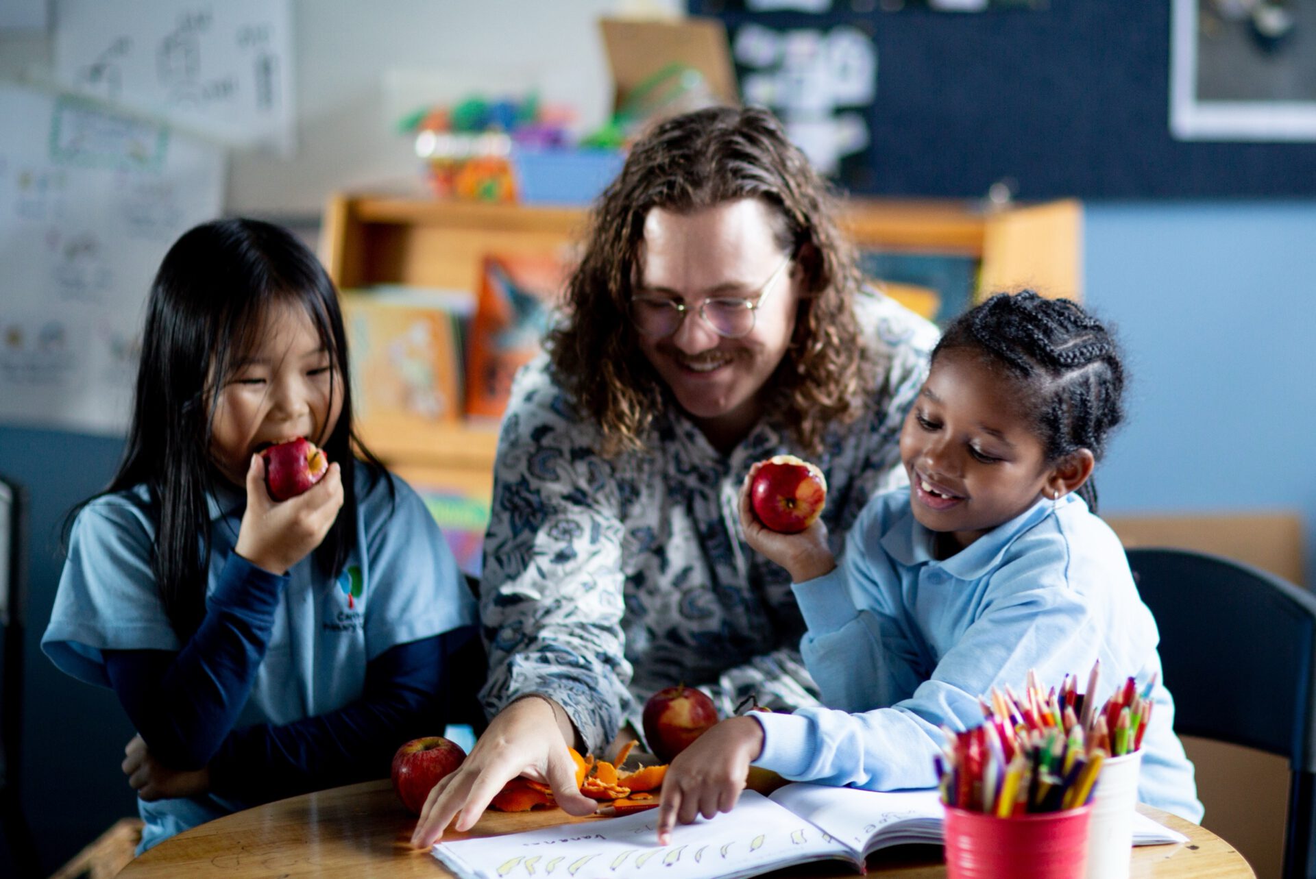 A teacher sharing apples with students in a classroom
