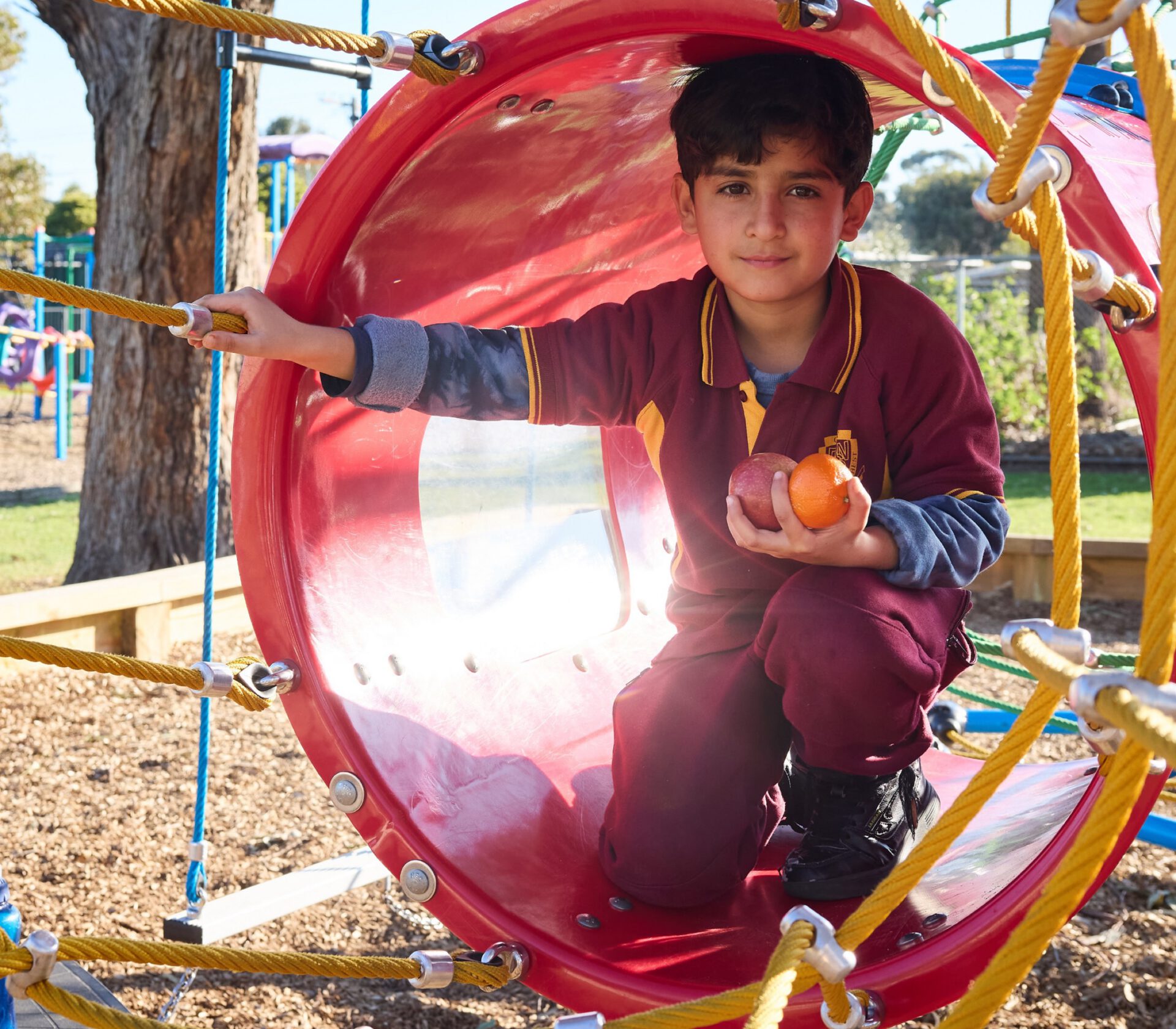 A schoolboy with an orange in a playground tunnel