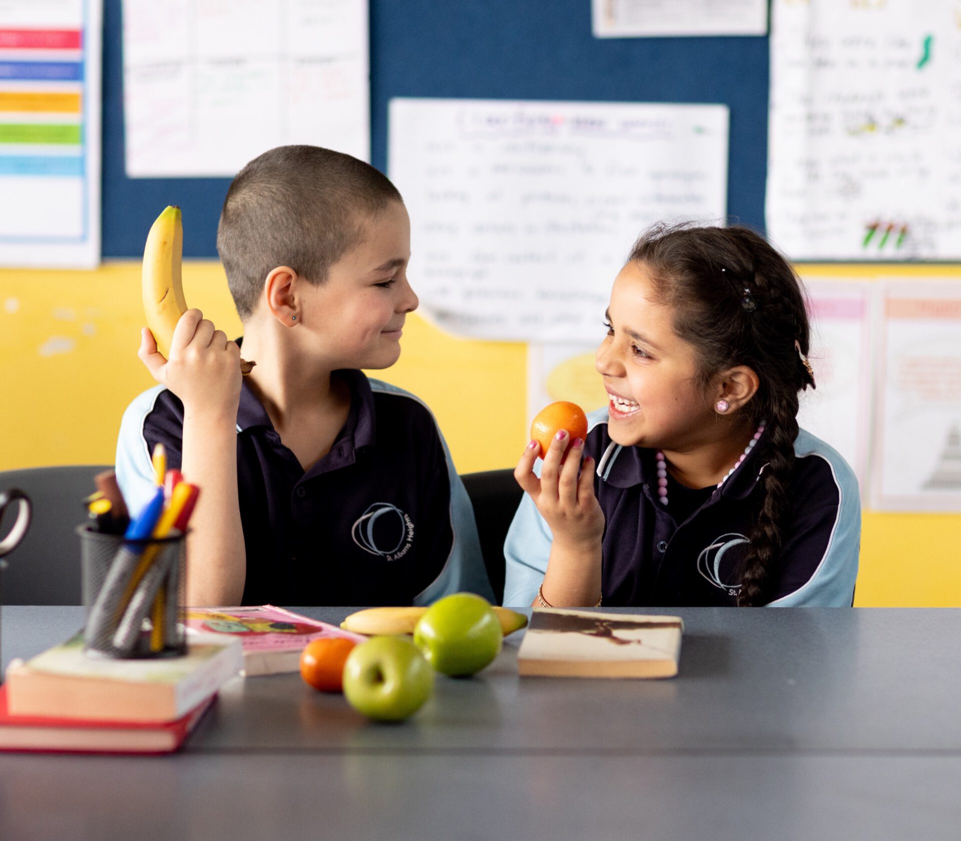 Two students sharing fresh fruit in a classroom
